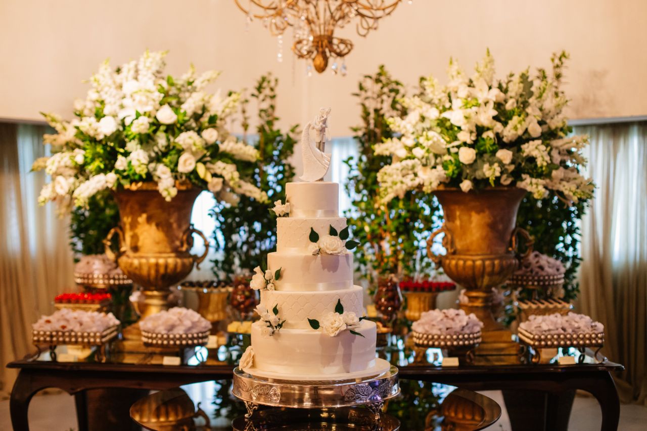 Mesa decorada com bolo de casamento de cinco andares com doces e flores